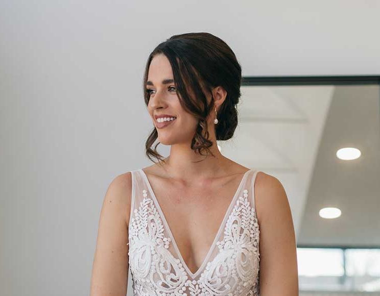 A woman in a wedding dress is smiling in front of a mirror.