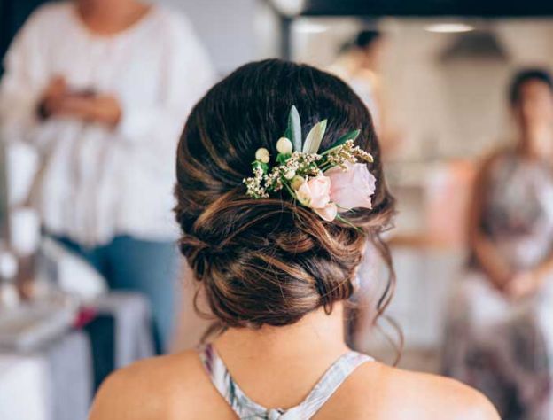 A woman with flowers in her hair is getting her hair done.