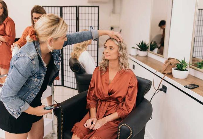 A woman is getting her hair done in a salon while sitting in a chair.