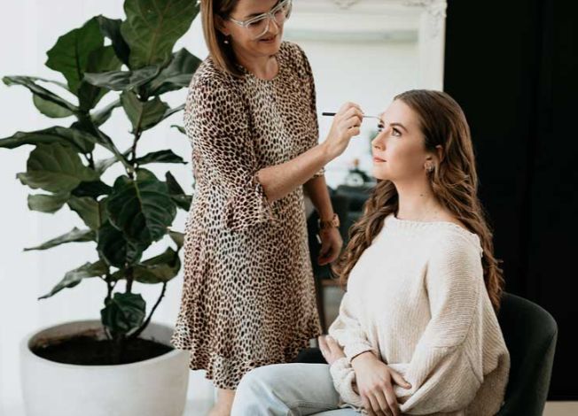 A woman is applying makeup to another woman 's face.