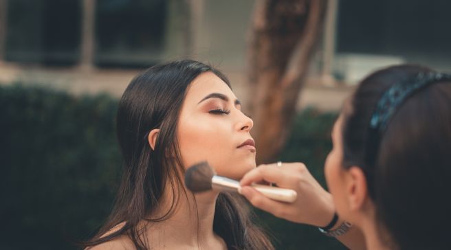 A woman is applying makeup to another woman 's face.