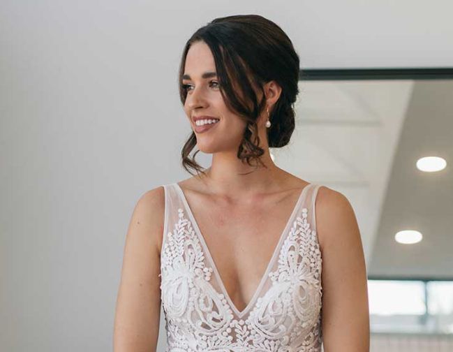 A woman in a wedding dress is standing in front of a mirror.