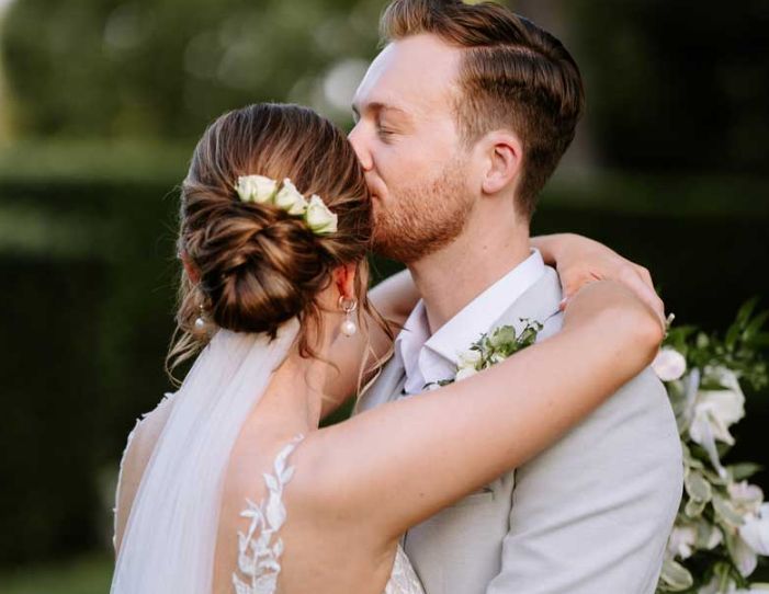 A bride and groom are kissing on their wedding day.