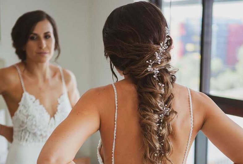 A woman in a wedding dress is looking at herself in the mirror.