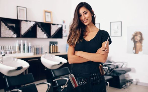 A woman is standing in a hair salon with her arms crossed.