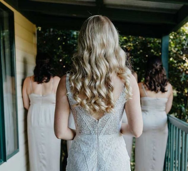 A woman in a white dress is standing on a balcony with her bridesmaids.