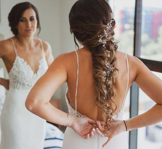 A woman in a wedding dress is looking at herself in the mirror.