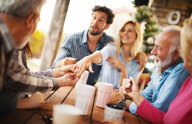 A group of people are sitting around a table talking to each other.