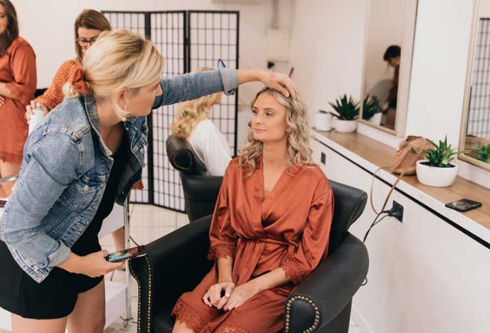 A woman is getting her hair done in a salon while sitting in a chair.