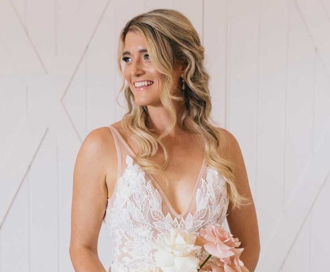 A woman in a wedding dress is holding a bouquet of flowers and smiling.