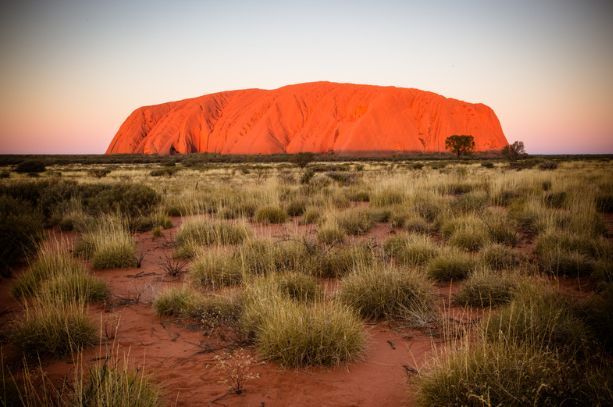 There is a large rock in the middle of the desert.