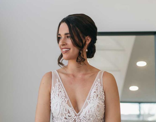 A woman in a wedding dress is standing in front of a mirror.