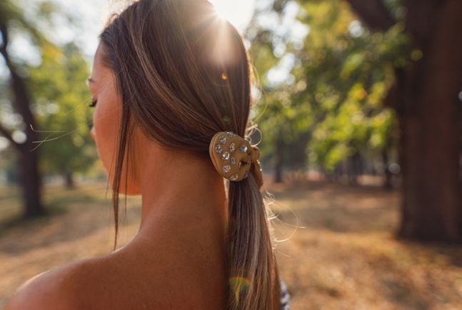 A woman is wearing a ponytail with a scrunchie in her hair.