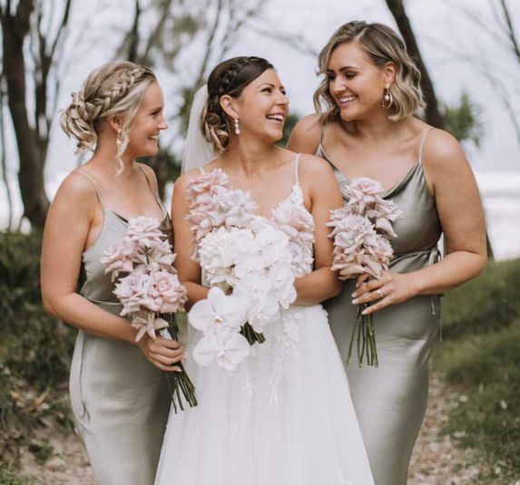 A bride and her bridesmaids are standing next to each other holding bouquets of flowers.