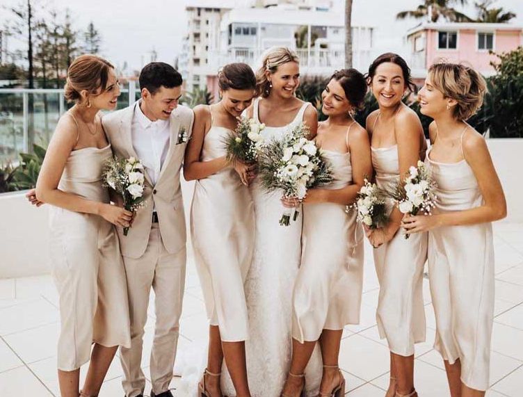 The bride and groom are posing for a picture with their bridesmaids.