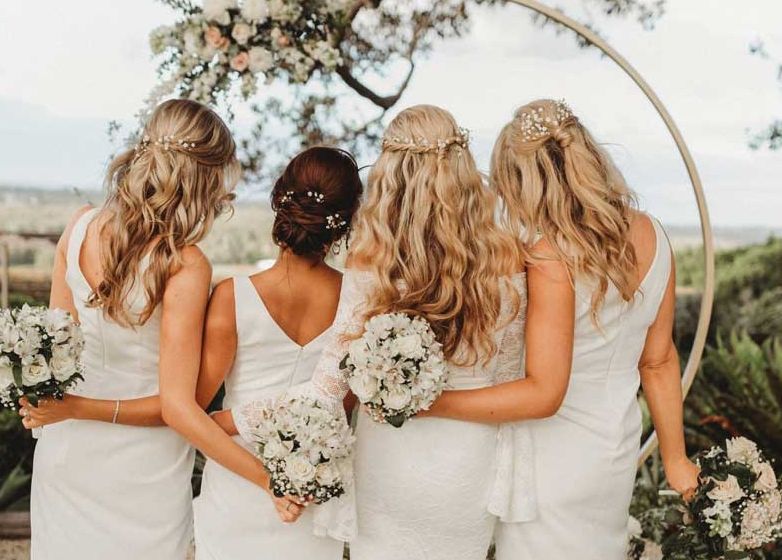 A bride and her bridesmaids are posing for a picture.