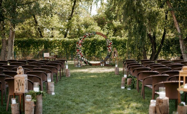 A row of chairs are lined up in a field for a wedding ceremony.