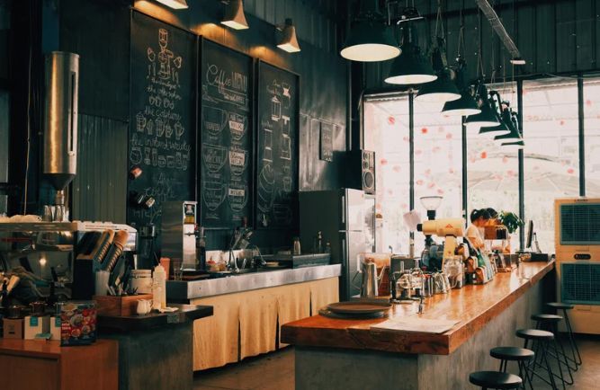 A coffee shop with a long wooden counter and stools.