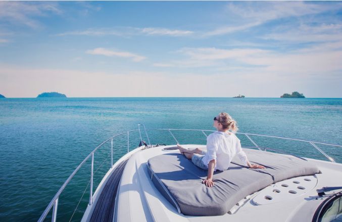 A woman is sitting on the bow of a boat in the ocean.