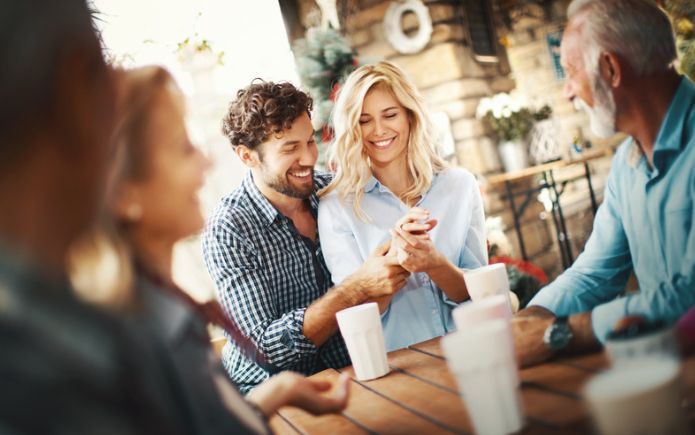 A group of people are sitting around a table drinking coffee.