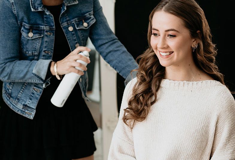 A woman is getting her hair done by a hairdresser in a salon.