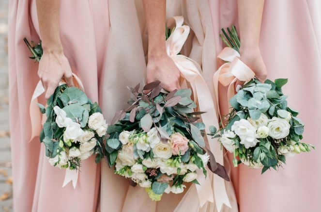 Three bridesmaids in pink dresses are holding bouquets of flowers.