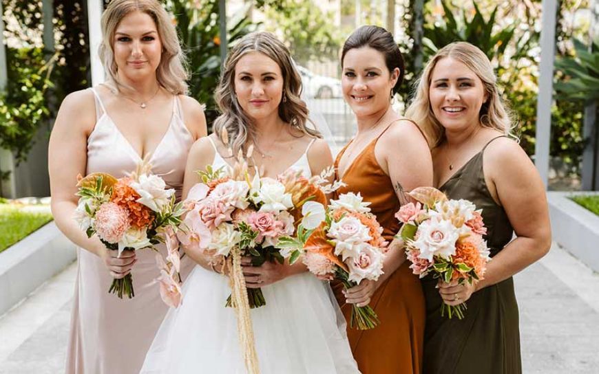 A bride and her bridesmaids are posing for a picture while holding bouquets of flowers.