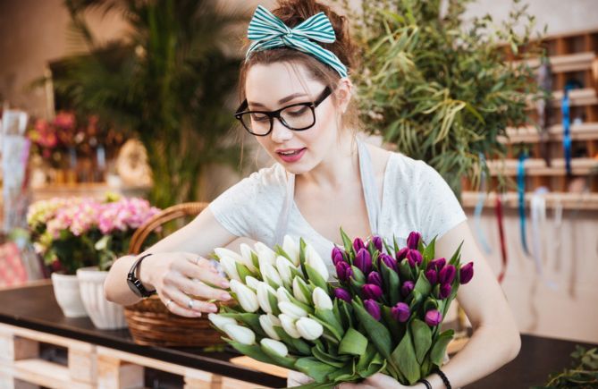 A woman is holding a bouquet of flowers in a flower shop.