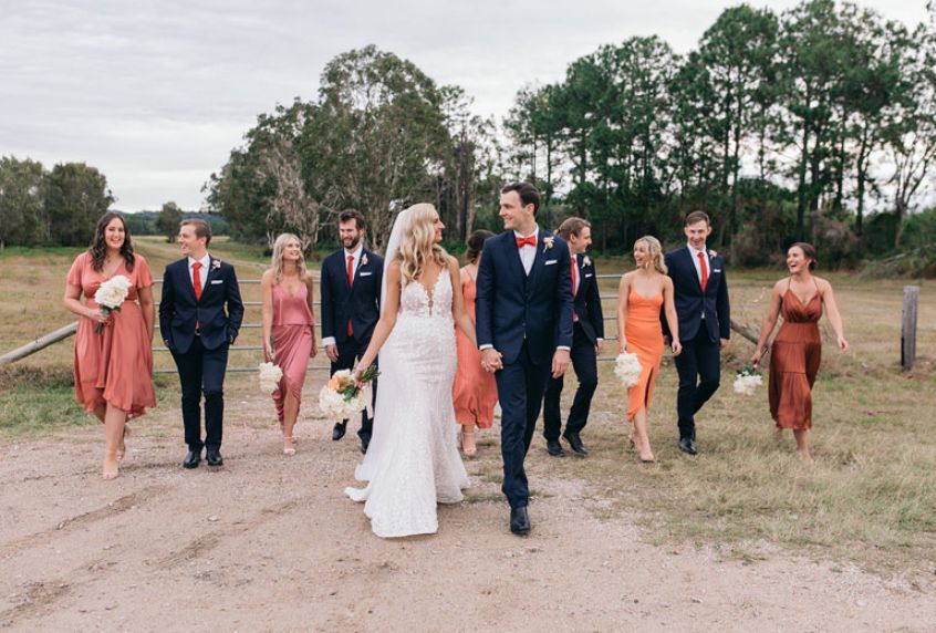 A bride and groom are walking with their wedding party.