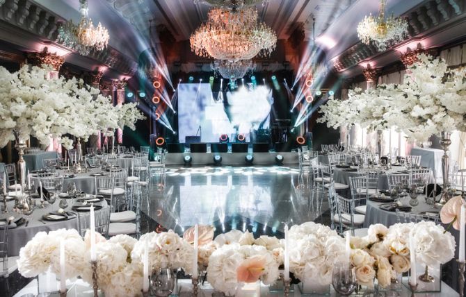 A large room filled with tables and chairs and a large screen on the wall.