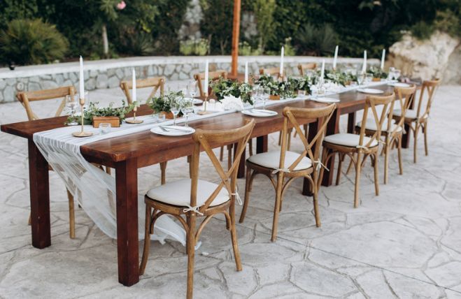 A long wooden table with chairs and plates on it.