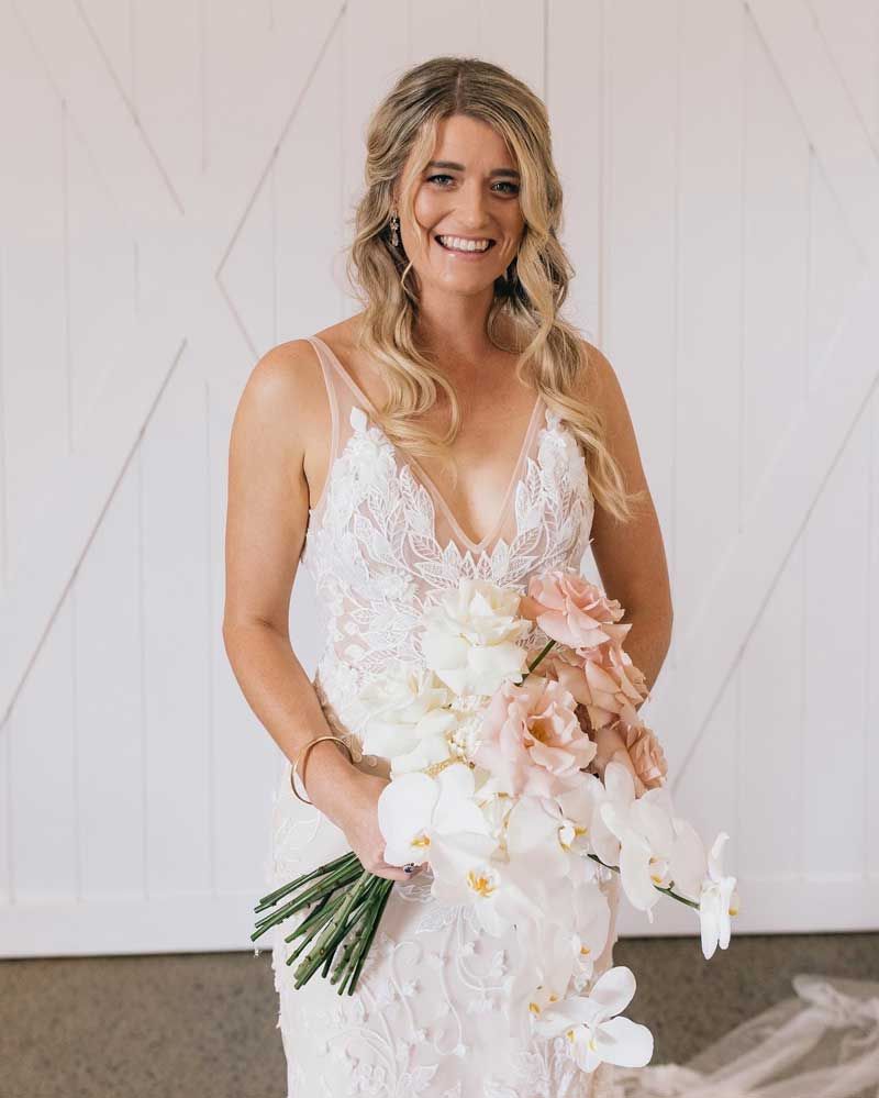 A woman in a wedding dress is holding a bouquet of flowers.