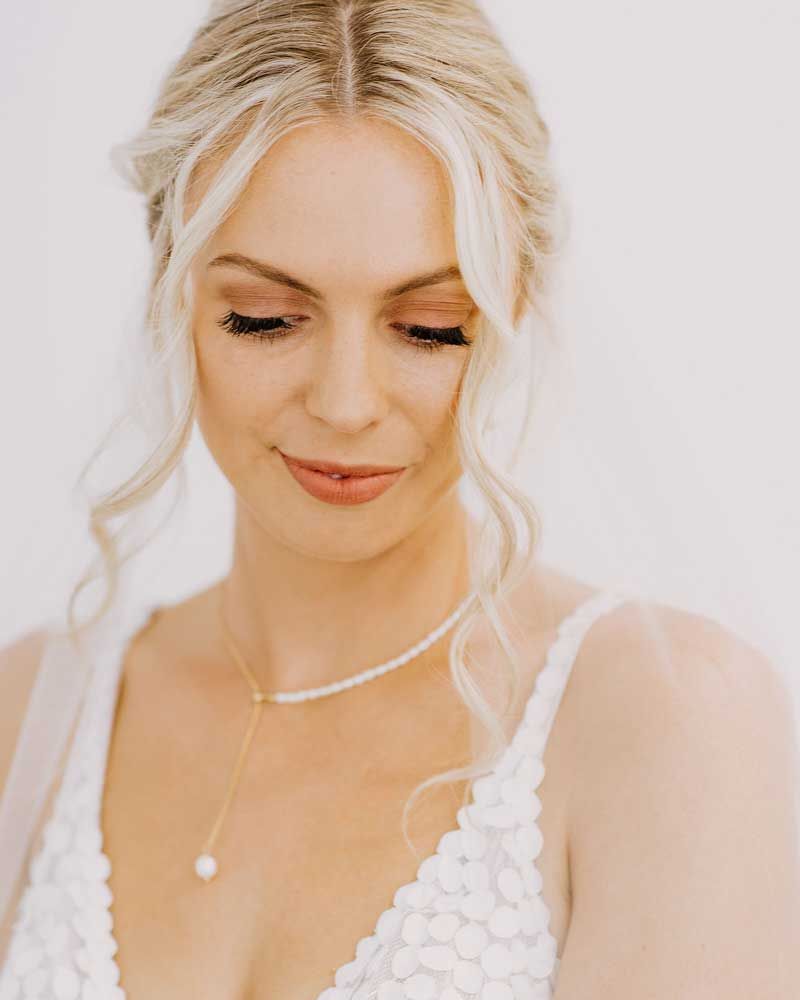 The bride is wearing a white dress and a pearl necklace.