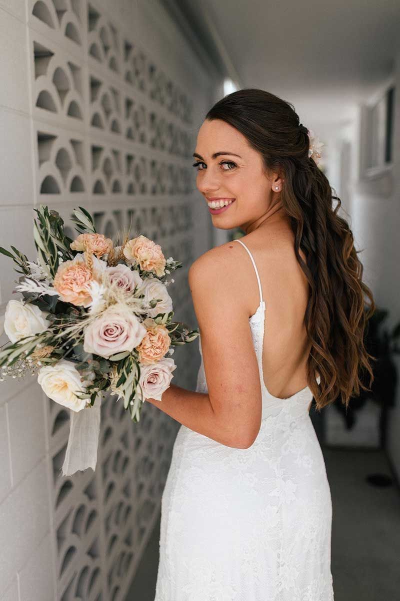 The bride is wearing a white dress and holding a bouquet of flowers.
