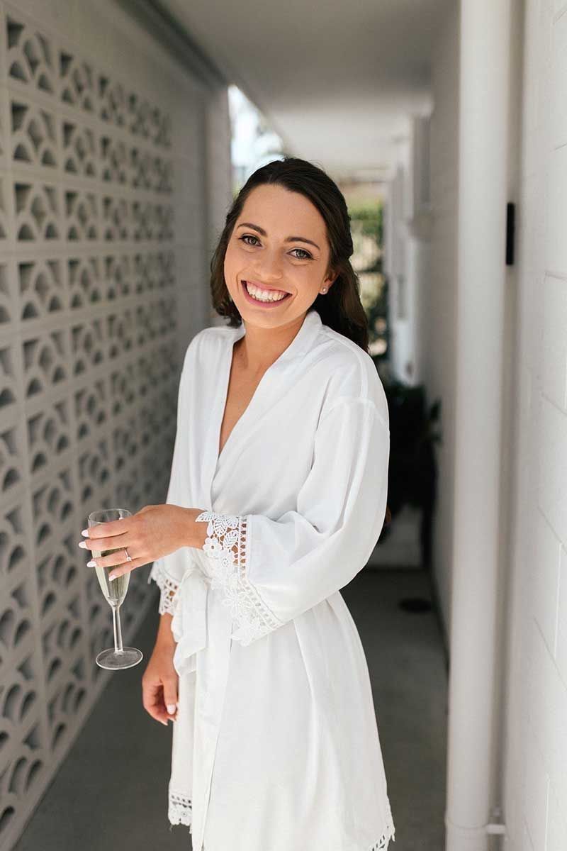 A woman in a white robe is holding a glass of champagne.
