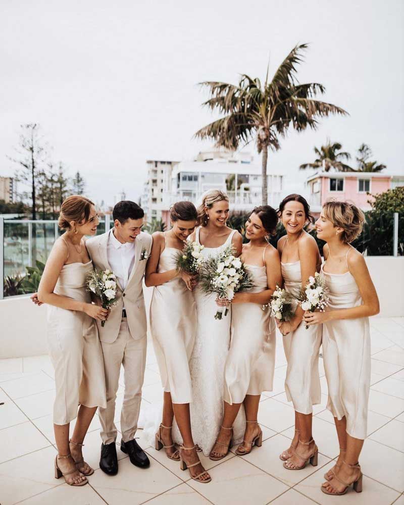 The bride and groom are posing for a picture with their bridesmaids.
