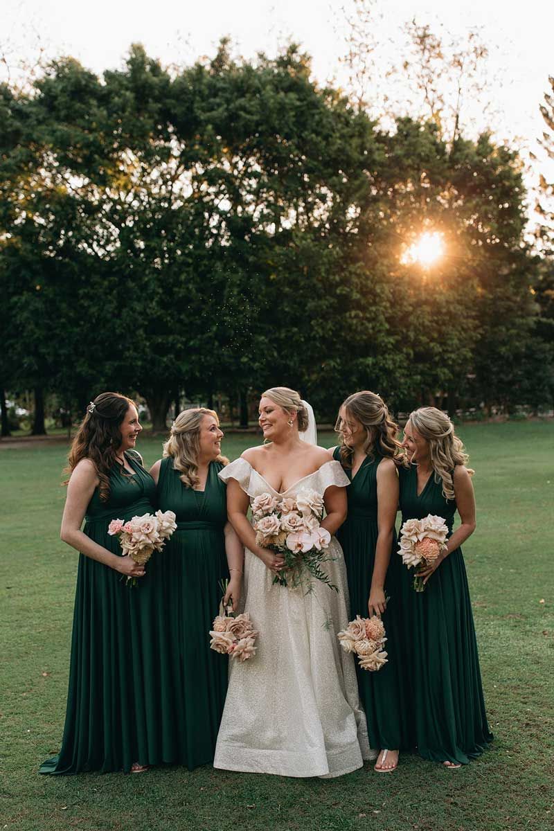 A bride and her bridesmaids are posing for a picture in a field.