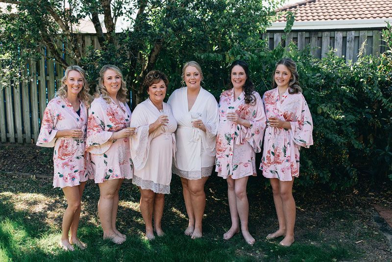 A group of women are standing next to each other in front of a fence.