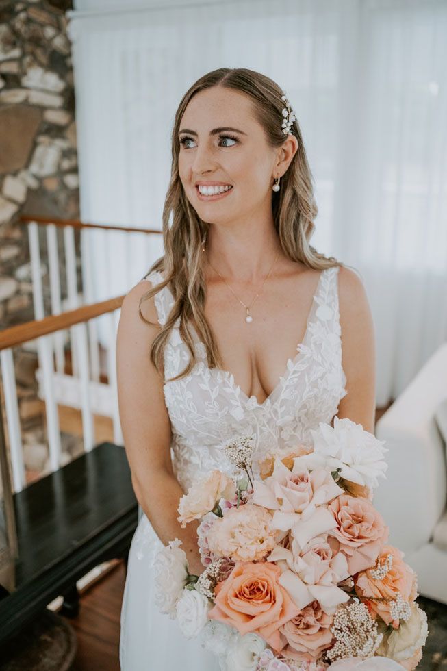 A bride in a wedding dress is holding a bouquet of flowers and smiling.