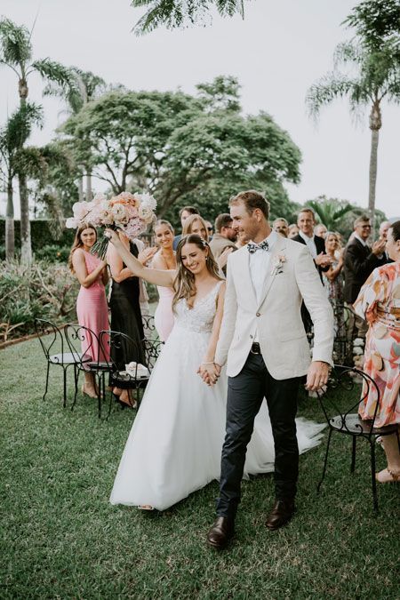 A bride and groom are walking down the aisle at their wedding holding hands.