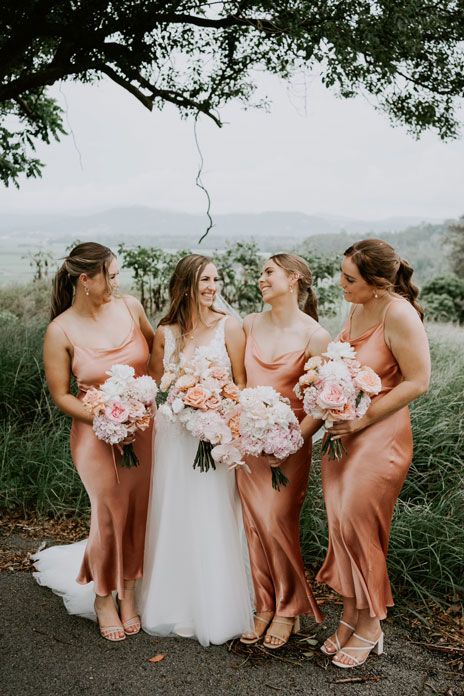 A bride and her bridesmaids are posing for a picture under a tree.