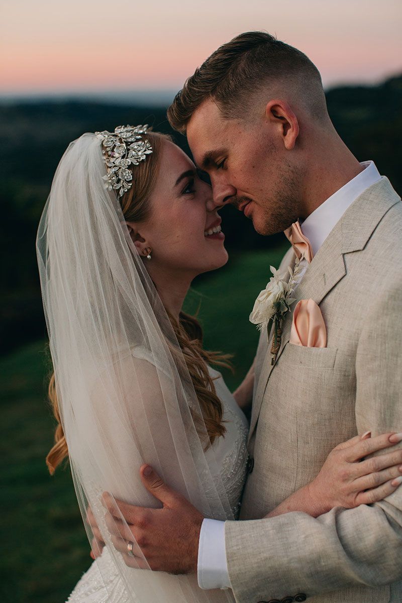 A bride and groom are kissing in a field.