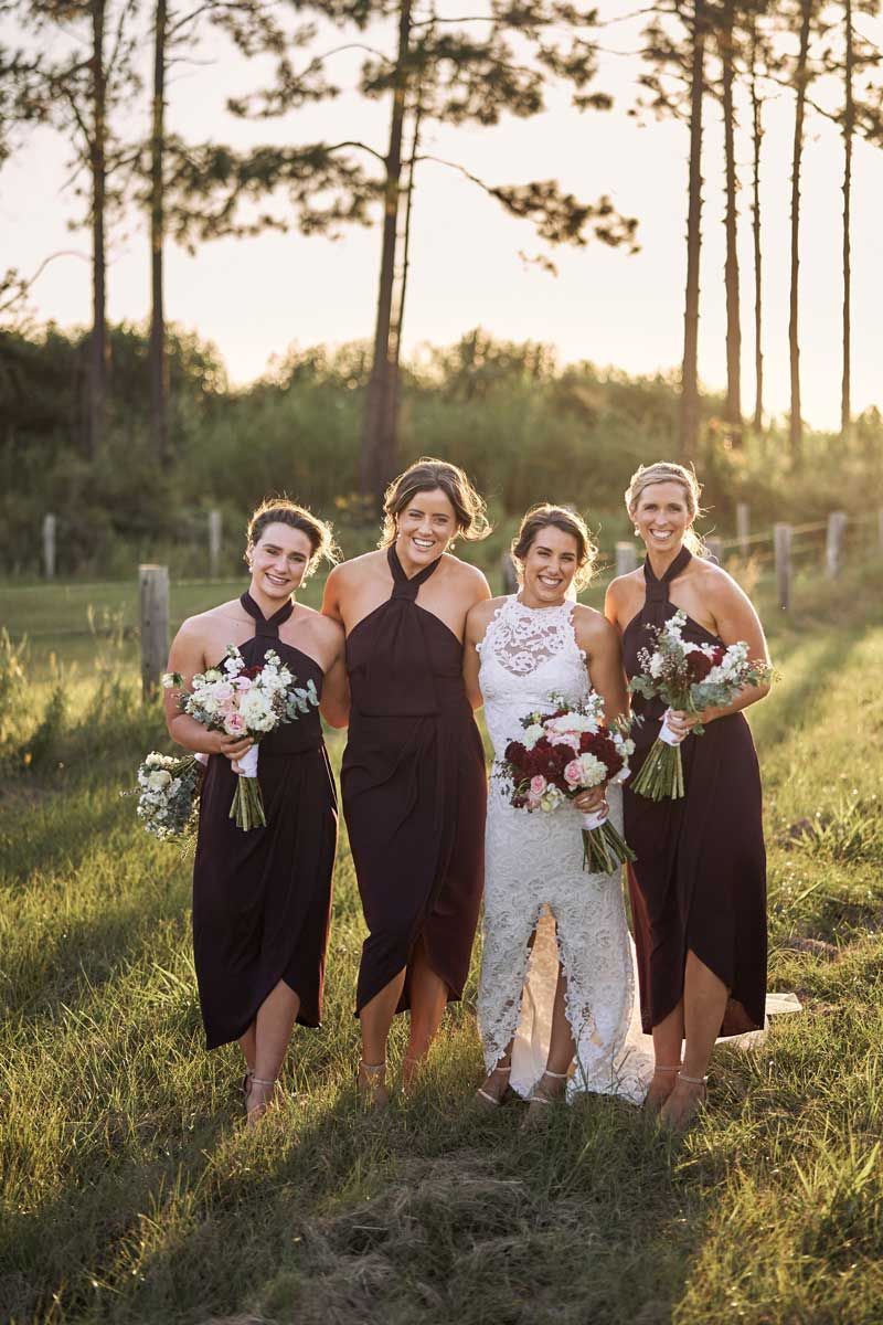 A bride and her bridesmaids are posing for a picture in a field.