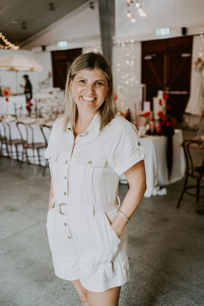 A woman in a white dress is standing in a room with tables and chairs.