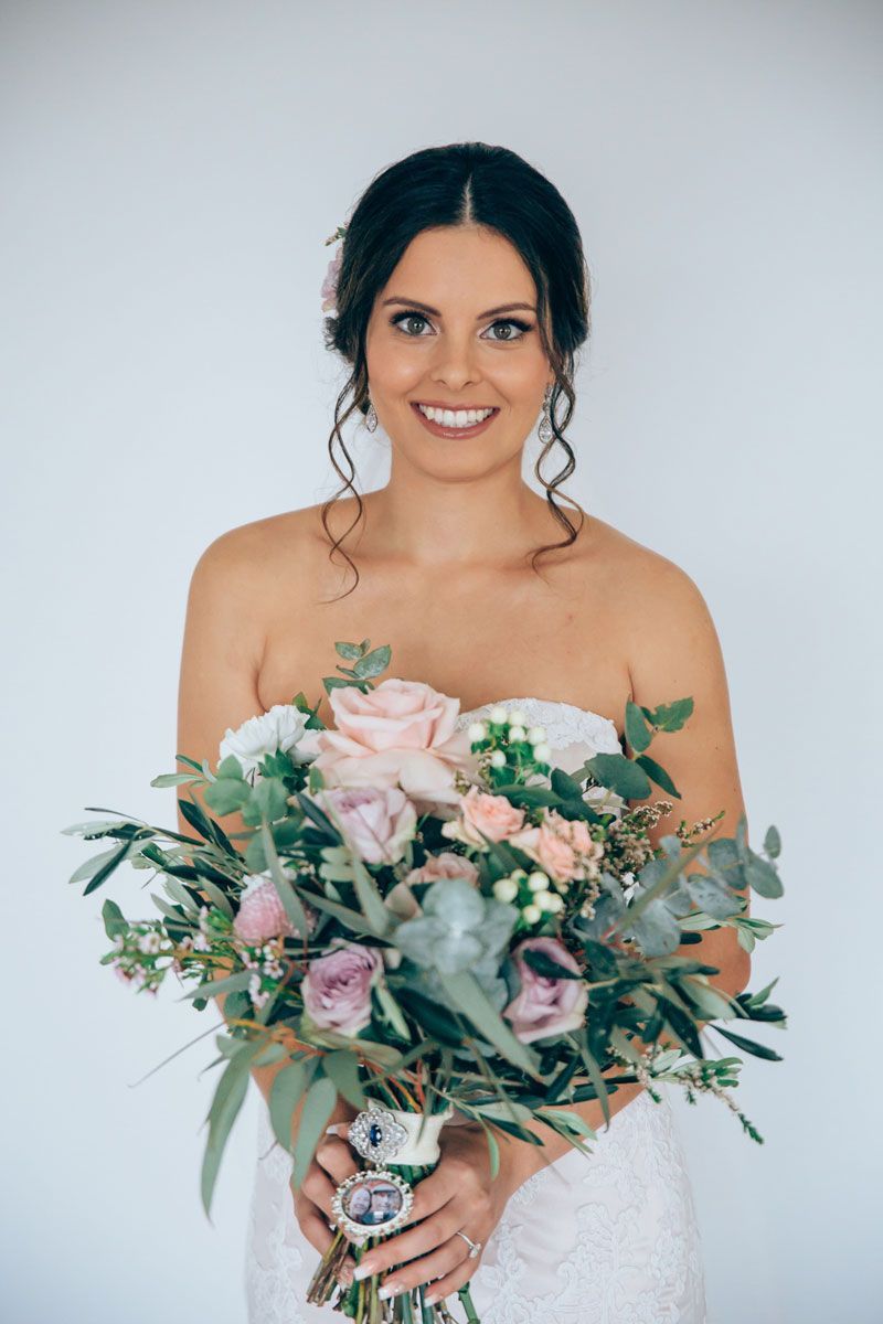 A woman in a wedding dress is holding a bouquet of flowers.