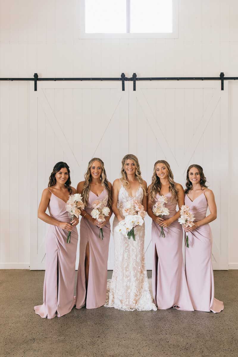 A bride and her bridesmaids are posing for a picture in a room.
