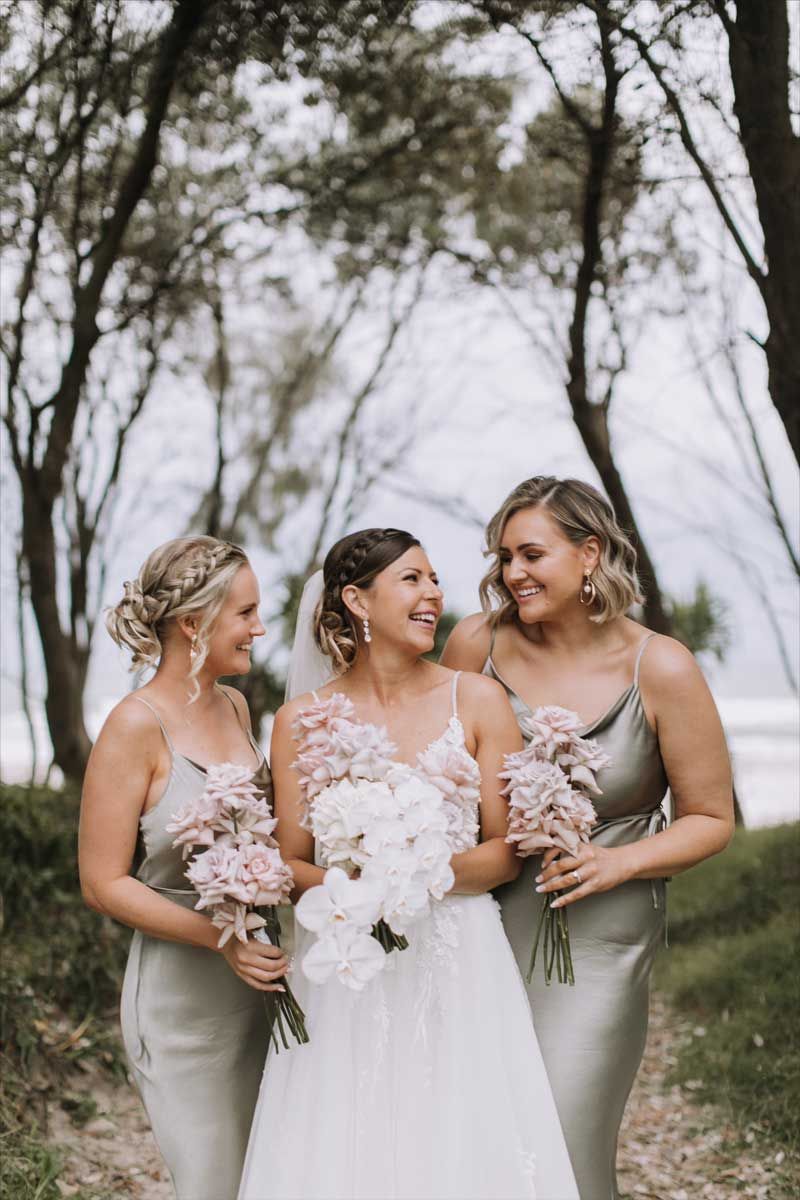 A bride and her bridesmaids are standing next to each other in a forest.