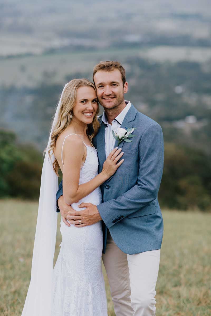 A bride and groom are posing for a picture in a field.