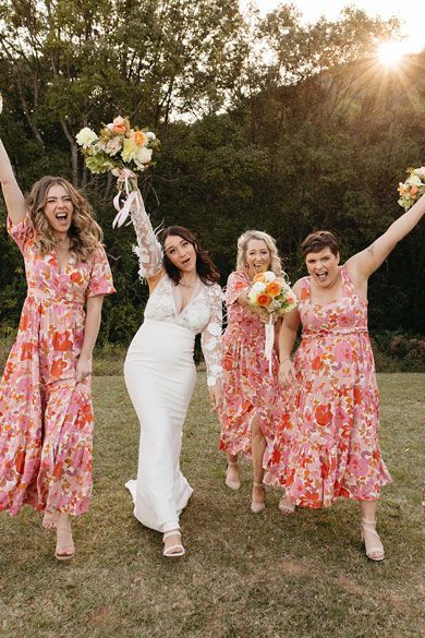 A bride and her bridesmaids are posing for a picture in a field.