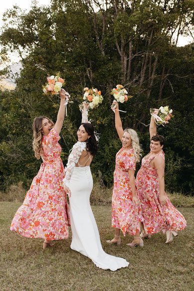 A bride and her bridesmaids are posing for a picture in a field.